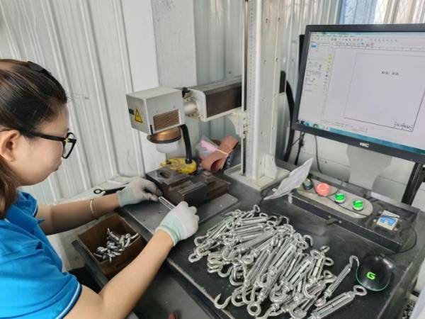 A worker engraves on the rigging with a machine.
